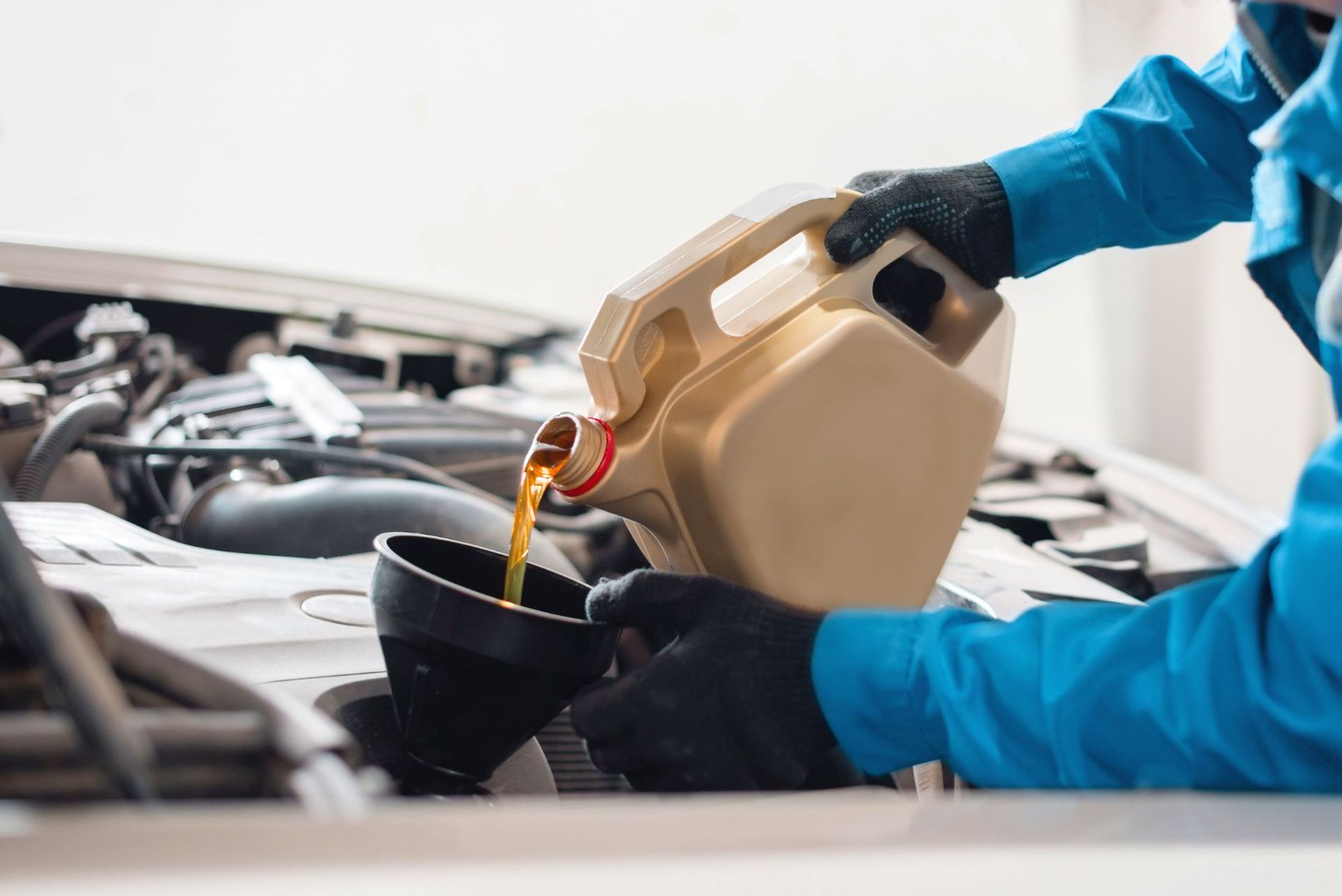 Service technician pouring motor oi into a funnel