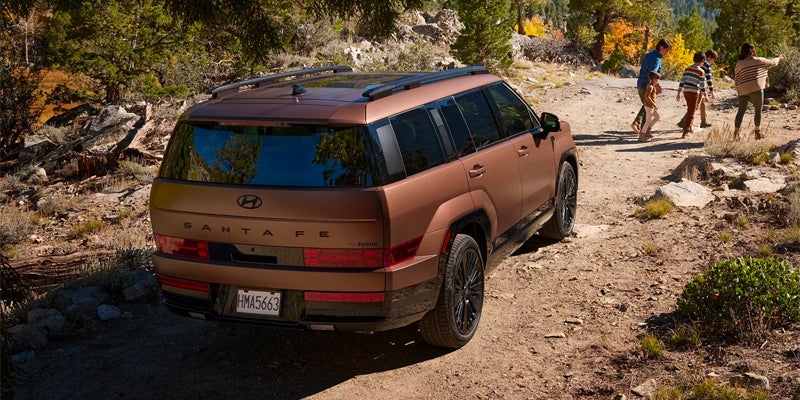 Hyundai Santa Fe Hybrid SUV rear view driving on a rugged outdoor trail.