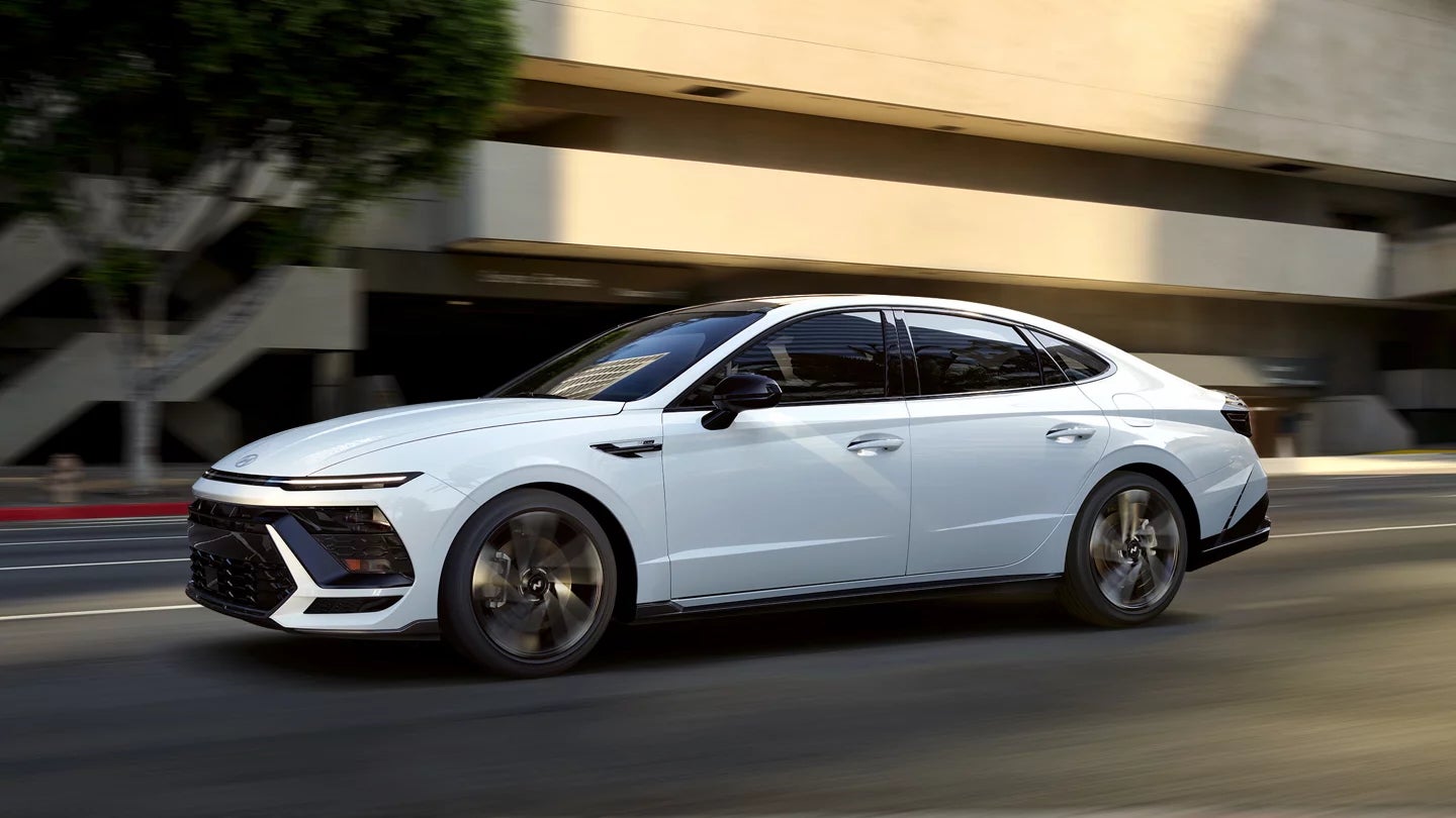 A white Hyundai Sonata driving through the city, showcasing its sleek modern design and aerodynamic profile.