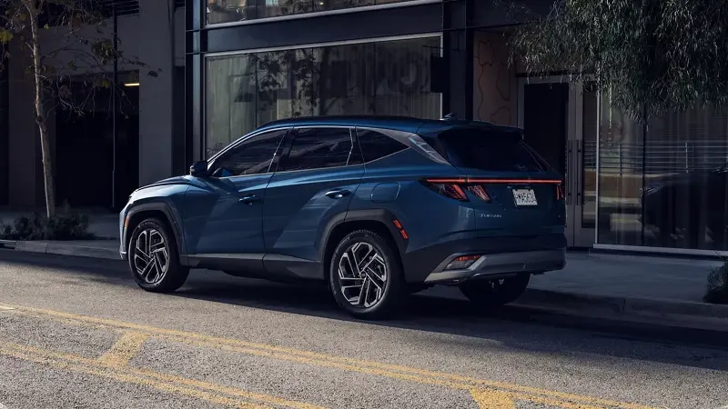 A blue Hyundai Tucson parked on a city street, showcasing its bold rear design and modern LED taillights.