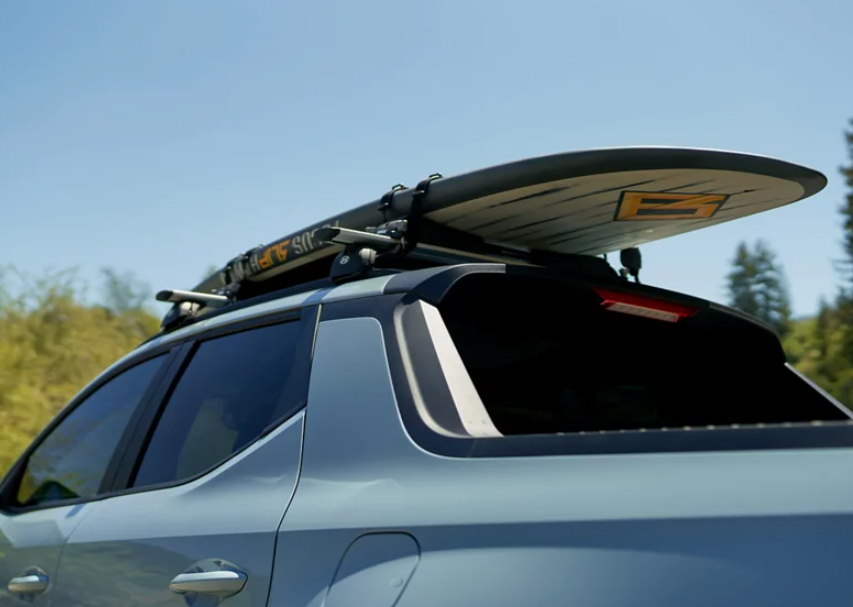 Hyundai Santa Cruz with a surfboard mounted on the roof.