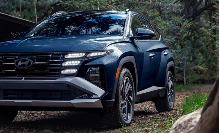 Blue Hyundai Tucson Hybrid parked in forest.