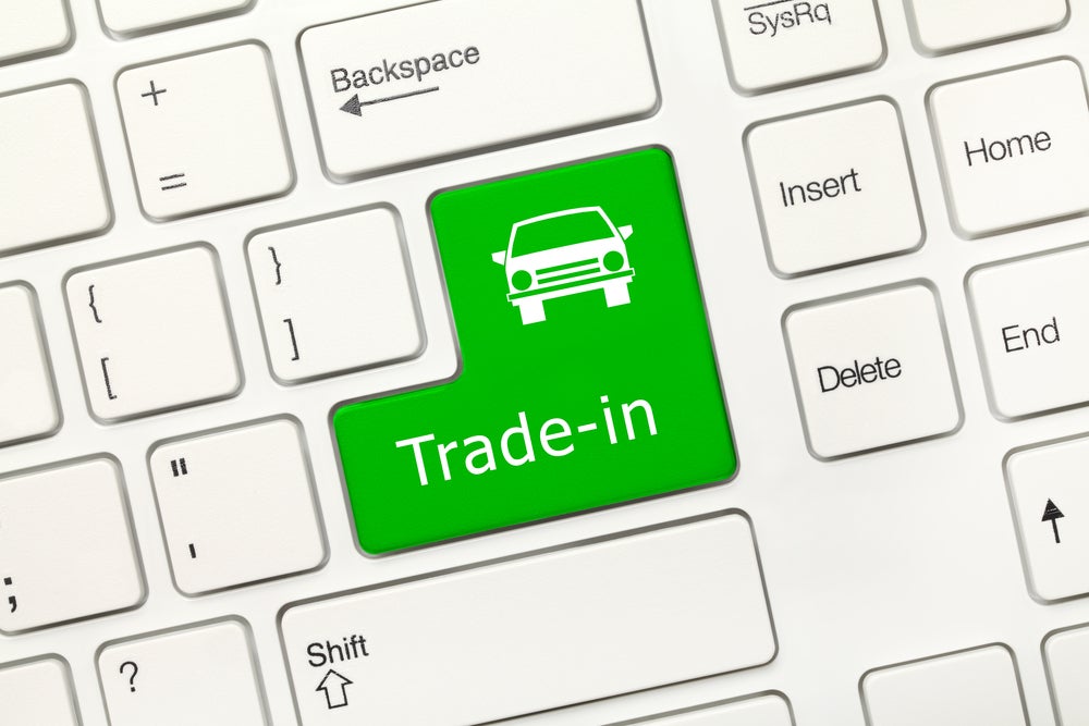 Green "Trade-in" button with car icon on a computer keyboard representing vehicle trade-in services.